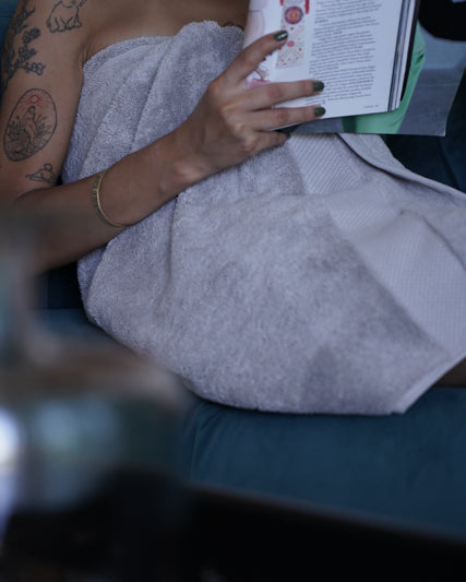 Woman wrapped in a Silver Suede Monte Rosa Aegean Cotton Organic Bath Towel after showering, showing its softness and luxurious feel