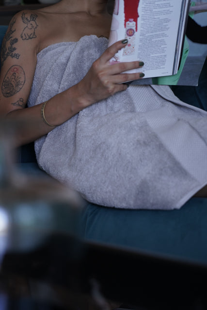 Woman wrapped in a Silver Suede Monte Rosa Aegean Cotton Organic Bath Towel after showering, showing its softness and luxurious feel