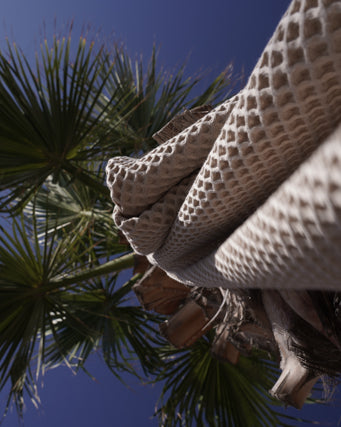 Minoa Seren organic cotton waffle luxury bath towels hanging from a tree, showcasing sustainable luxury with eco-friendly design and soft plush texture