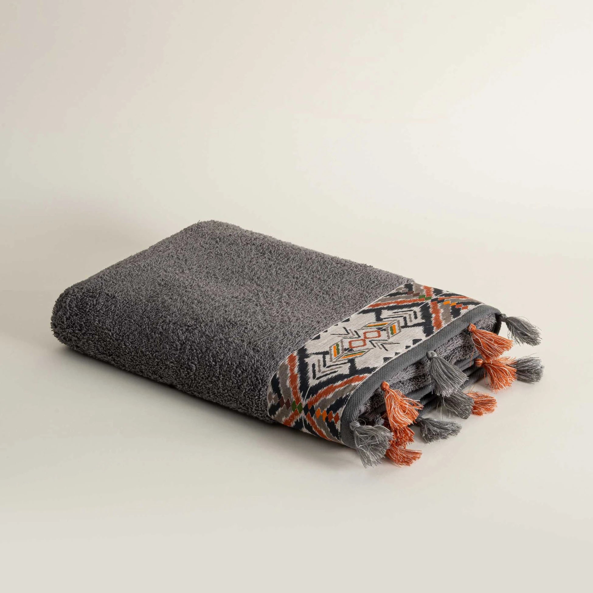 Folded textured towel with geometric pattern and tassels on a light background