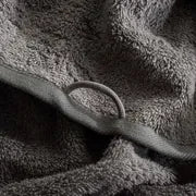 Close-up of a textured gray towel with a small ring on a gray background