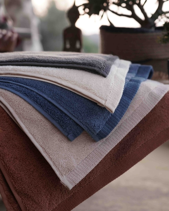 Stack of folded towels in various colors on a wooden surface with a blurred background
