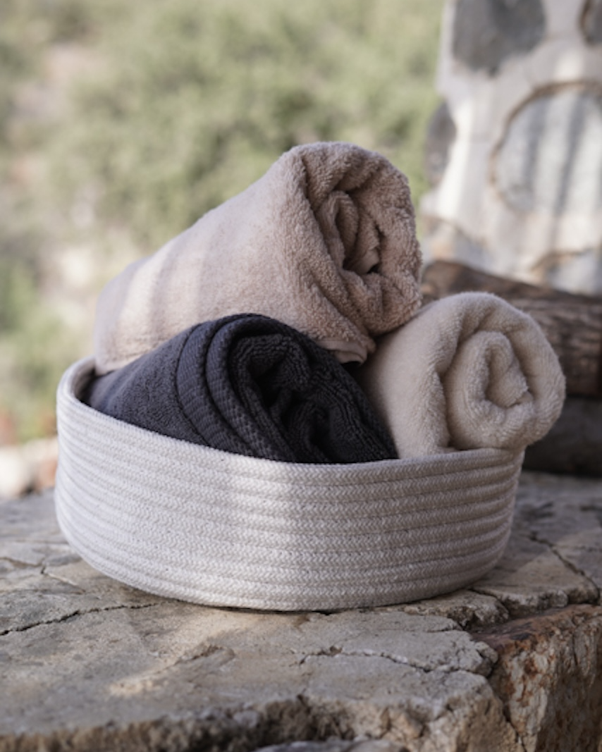 Folded towels in a woven basket on stone steps with a natural background