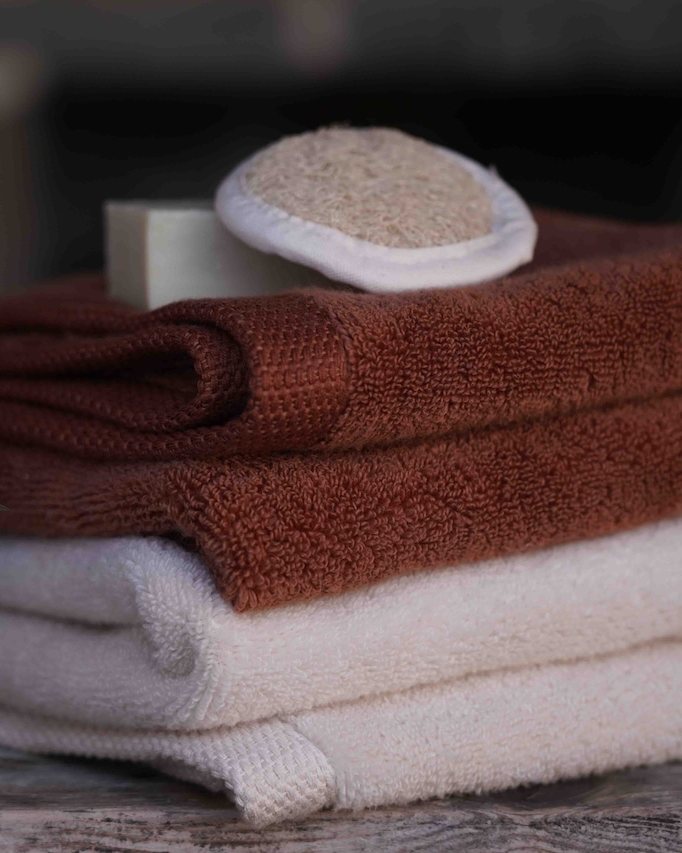 Stack of folded brown and white towels on a wooden surface with a blurred background