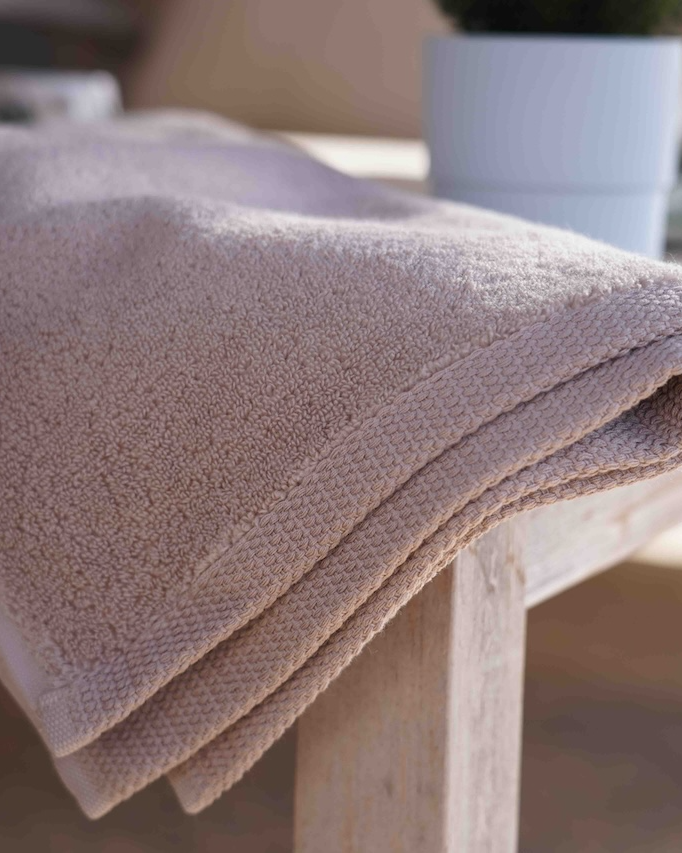 Folded beige towel on a wooden table with a blurred background