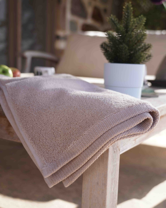 Beige towel draped over a wooden table with a blurred outdoor background