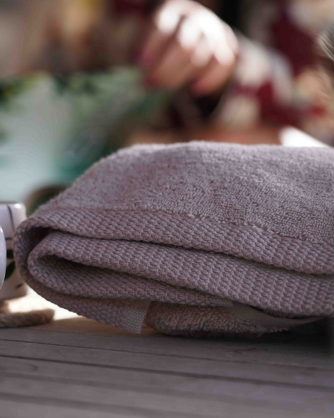 Grey towel and mug on a wooden surface with blurred background