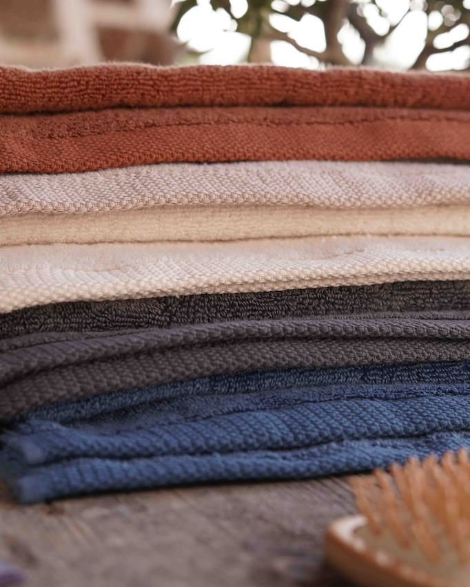 Stack of folded towels in various colors on a surface with a blurred background