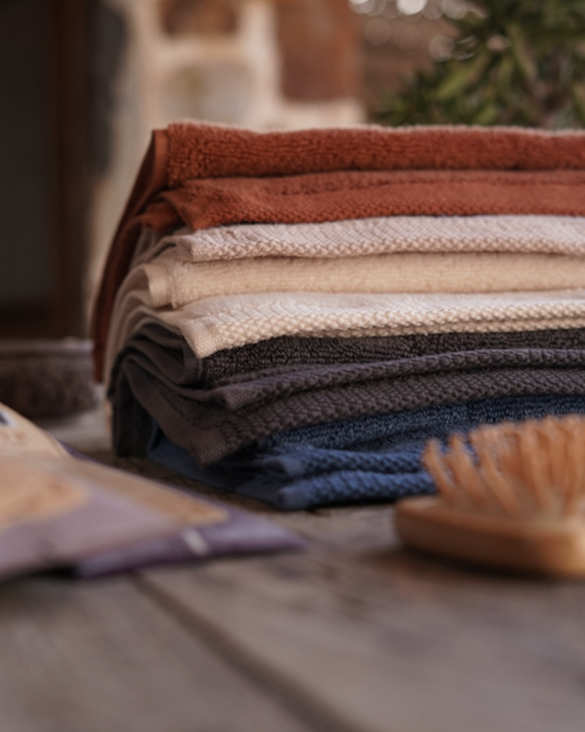 Stack of folded towel in various colors on a wooden surface.