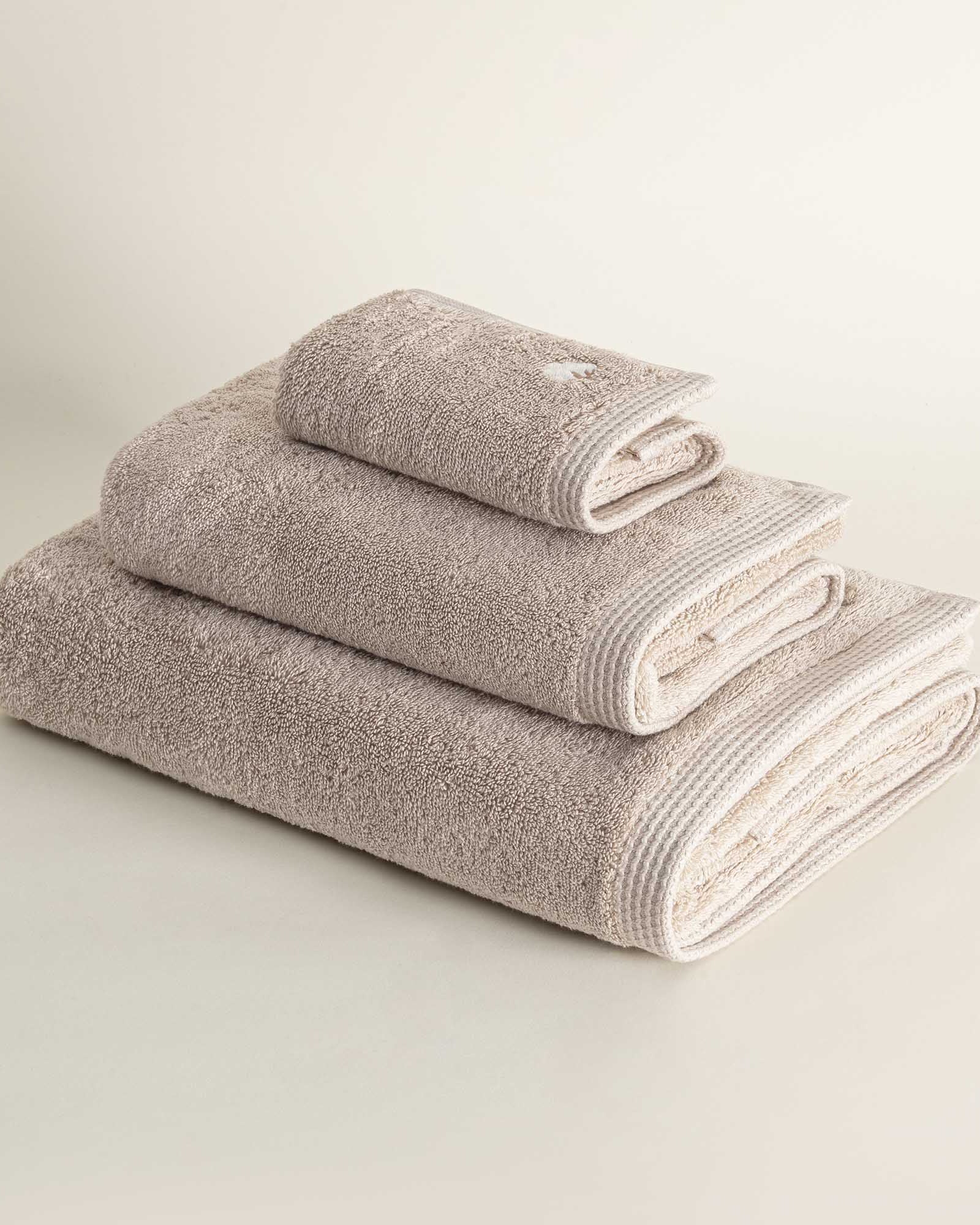 Side view of three folded Jasper 600-gram organic Aegean cotton luxury bath, hand, and washcloth towels in Vanilla Embrace, highlighting soft plush texture, warm color, and luxurious fabric