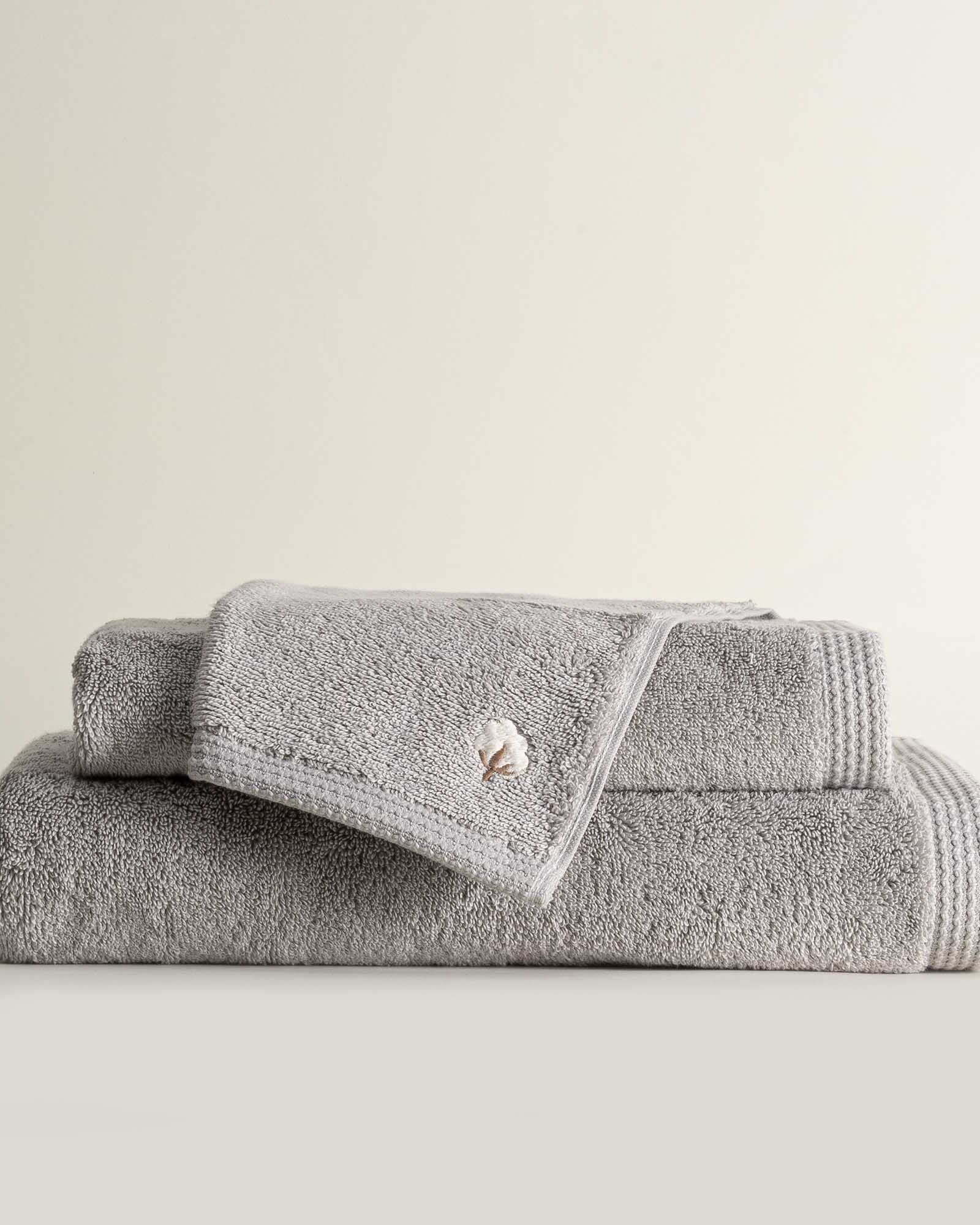 Three folded Jasper 600-gram organic Aegean cotton luxury bath, hand, and washcloth towels in Silver Symphony, showcasing soft plush texture, cool tone, and luxurious fabric