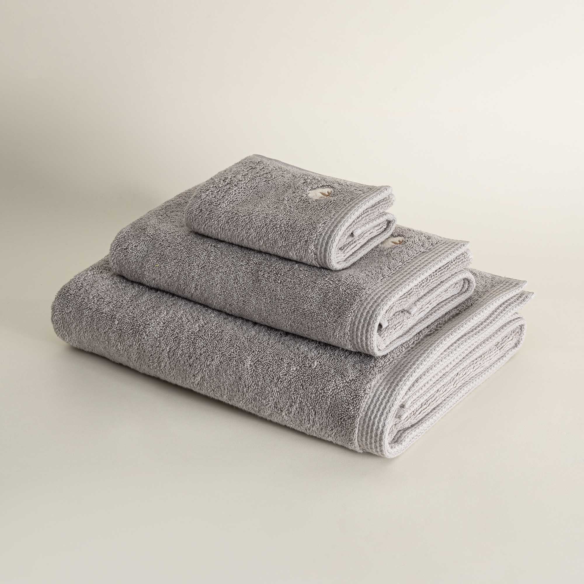 Side view of three folded Jasper 600-gram organic Aegean cotton luxury bath, hand, and washcloth towels in Silver Symphony, highlighting soft plush texture, cool tone, and luxurious fabric