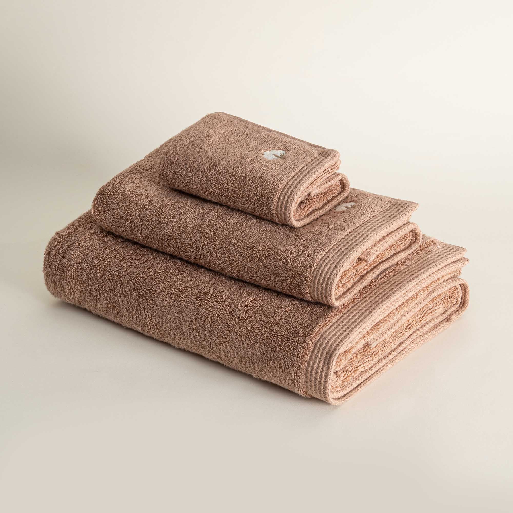 Side view of folded Jasper 600-gram organic Aegean cotton luxury bath, hand, and washcloth towels in Amber Amour, showcasing soft plush texture, rich tone, and luxurious fabric
