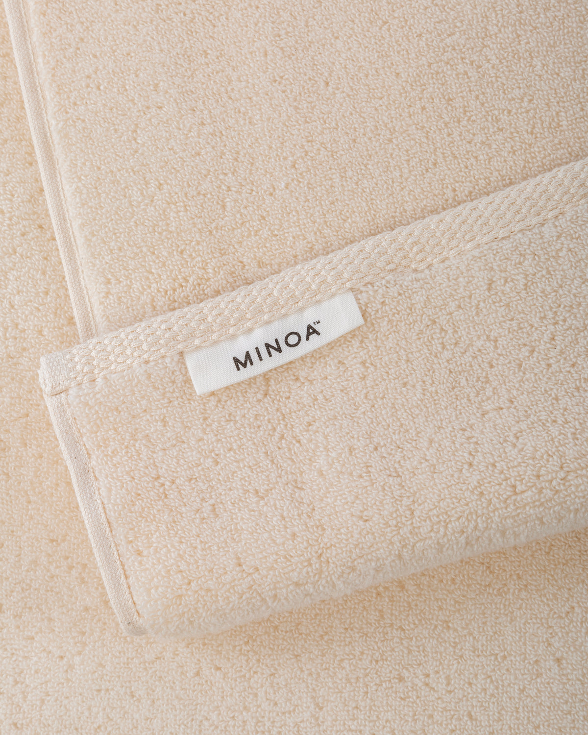 Close-up of a beige towels with a 'MINOA' label.