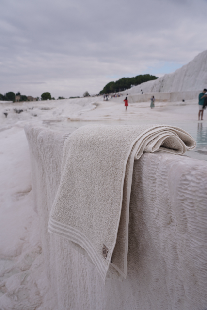 Beige towel draped over a textured surface with people and trees in the background