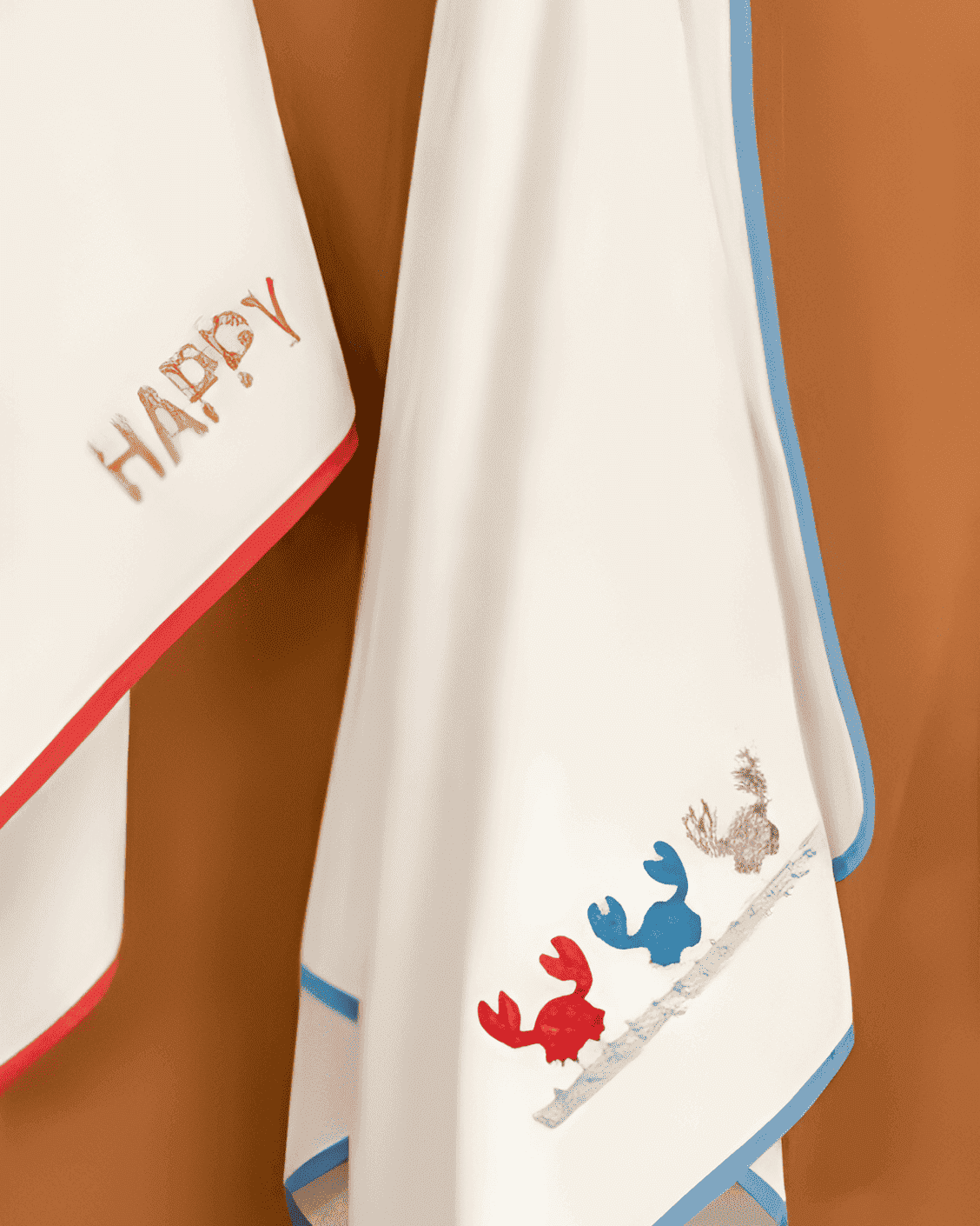 Two baby towels with embroidered designs on a brown background