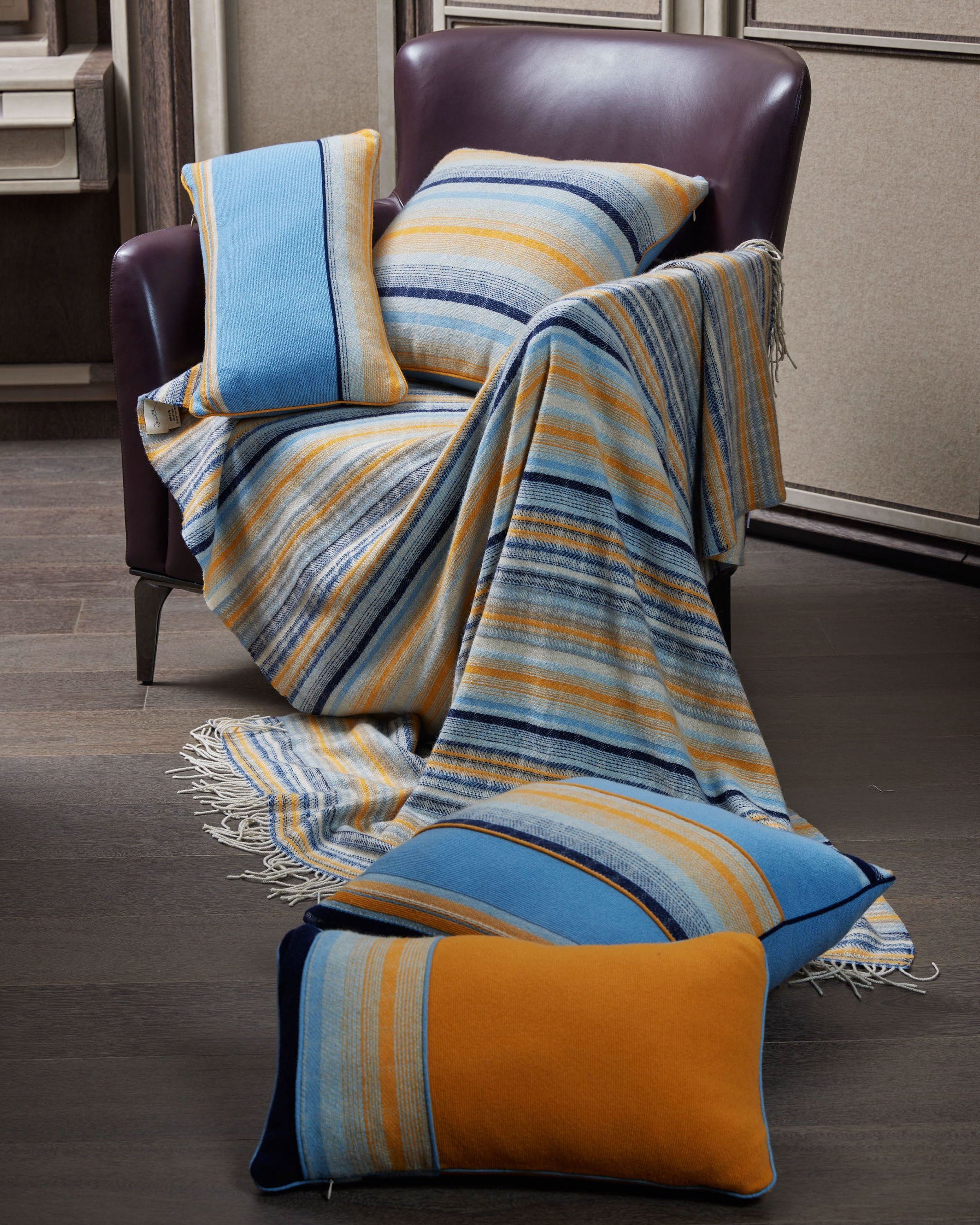 Bright orange and blue tones of line pattern cushions placed on sofa chair and floor