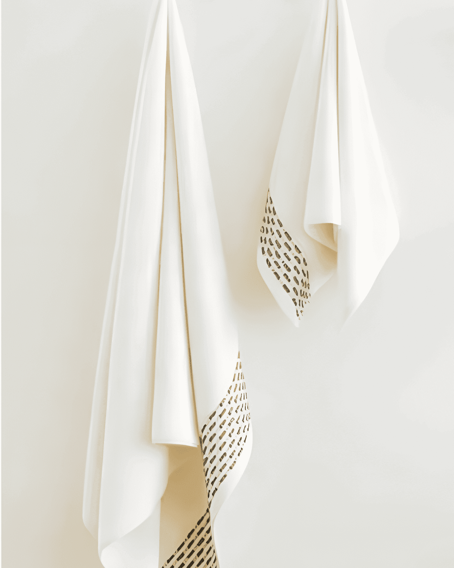 Two Calm 550-GSM Cotton Towels in ivory and green, organic cotton towels hanging on a towel hanger, showcasing their soft texture and soothing color combination.