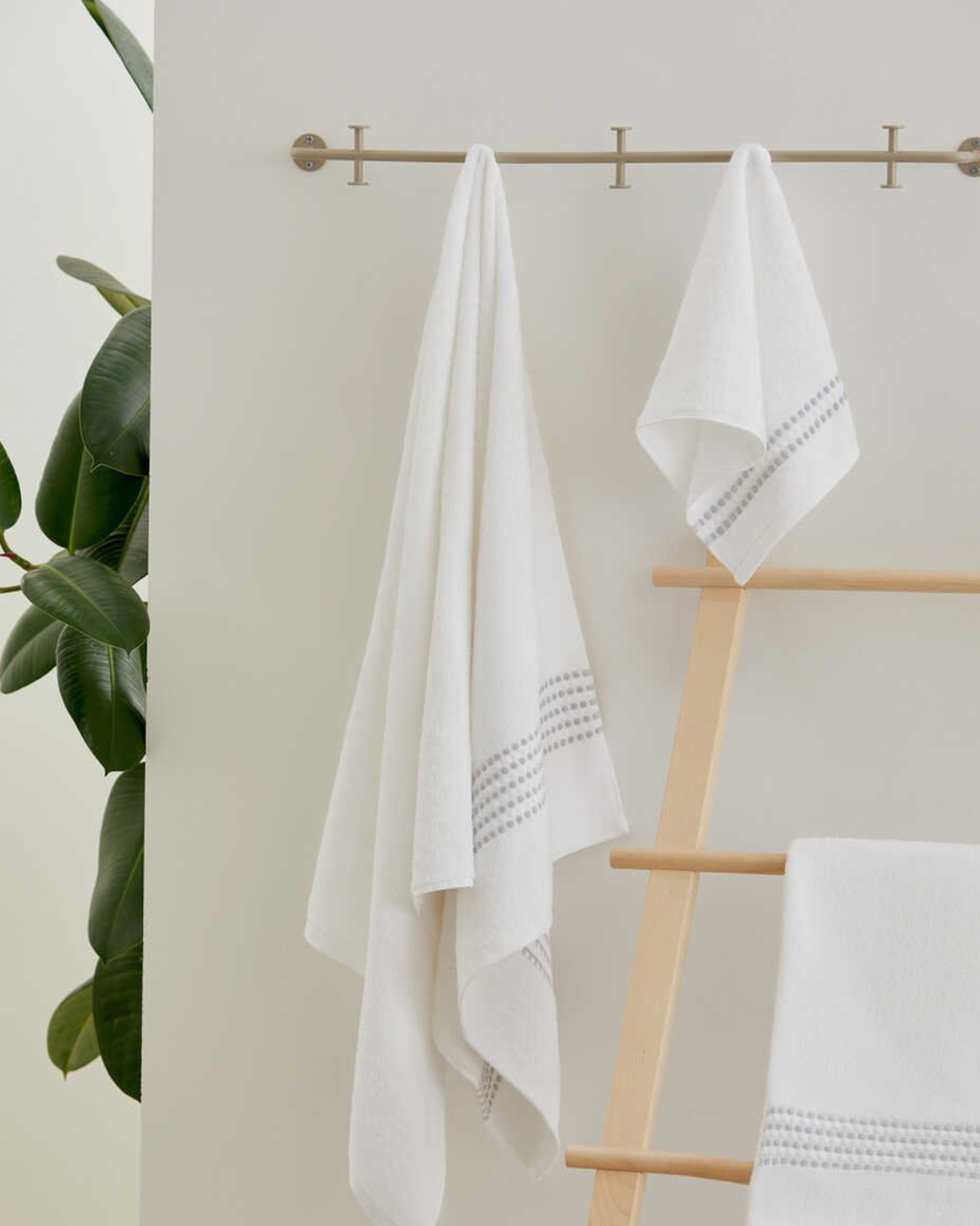 Two Classy 460-GSM Cotton/Viscose Towels in white, organic cotton towels hanging on a towel hanger, showcasing their soft texture and luxurious, fresh look.