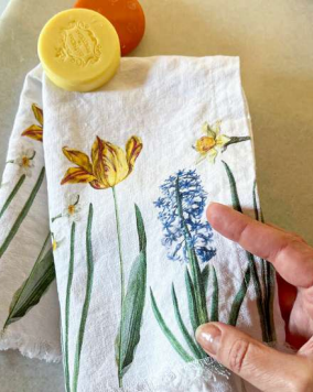Hand-drawn floral towel with a hand holding it, featuring yellow tulips and blue hyacinths.