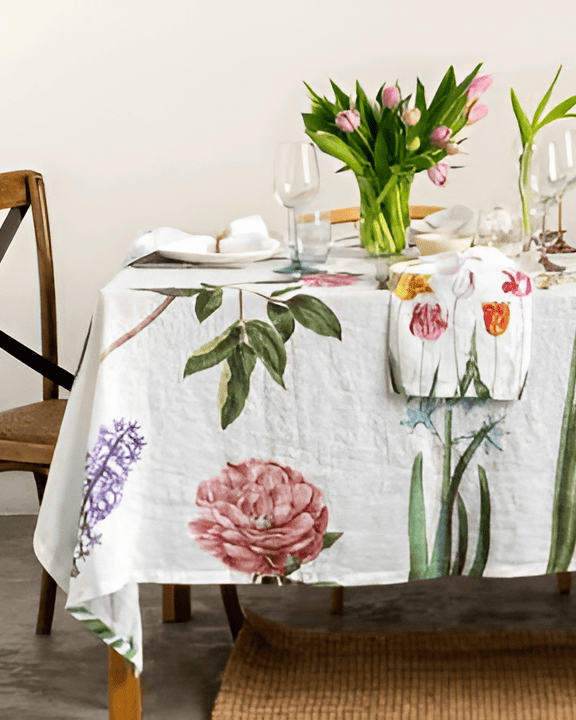 Table setting with floral tablecloth and tulips on a white wall background