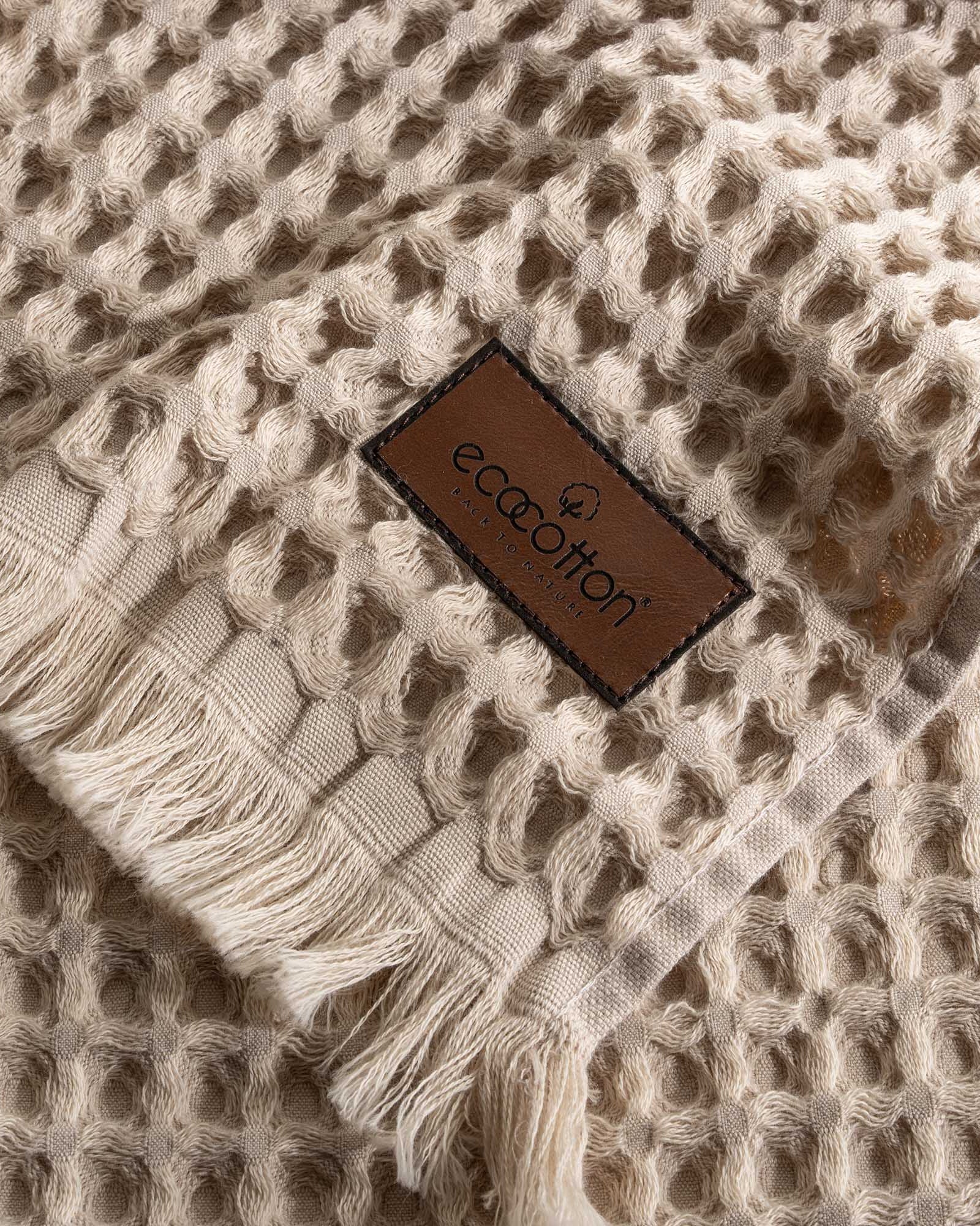Close-up of Ecocotton tag on Yummy Vanilla Seren organic cotton waffle luxury bath towel, highlighting sustainable luxury and soft texture