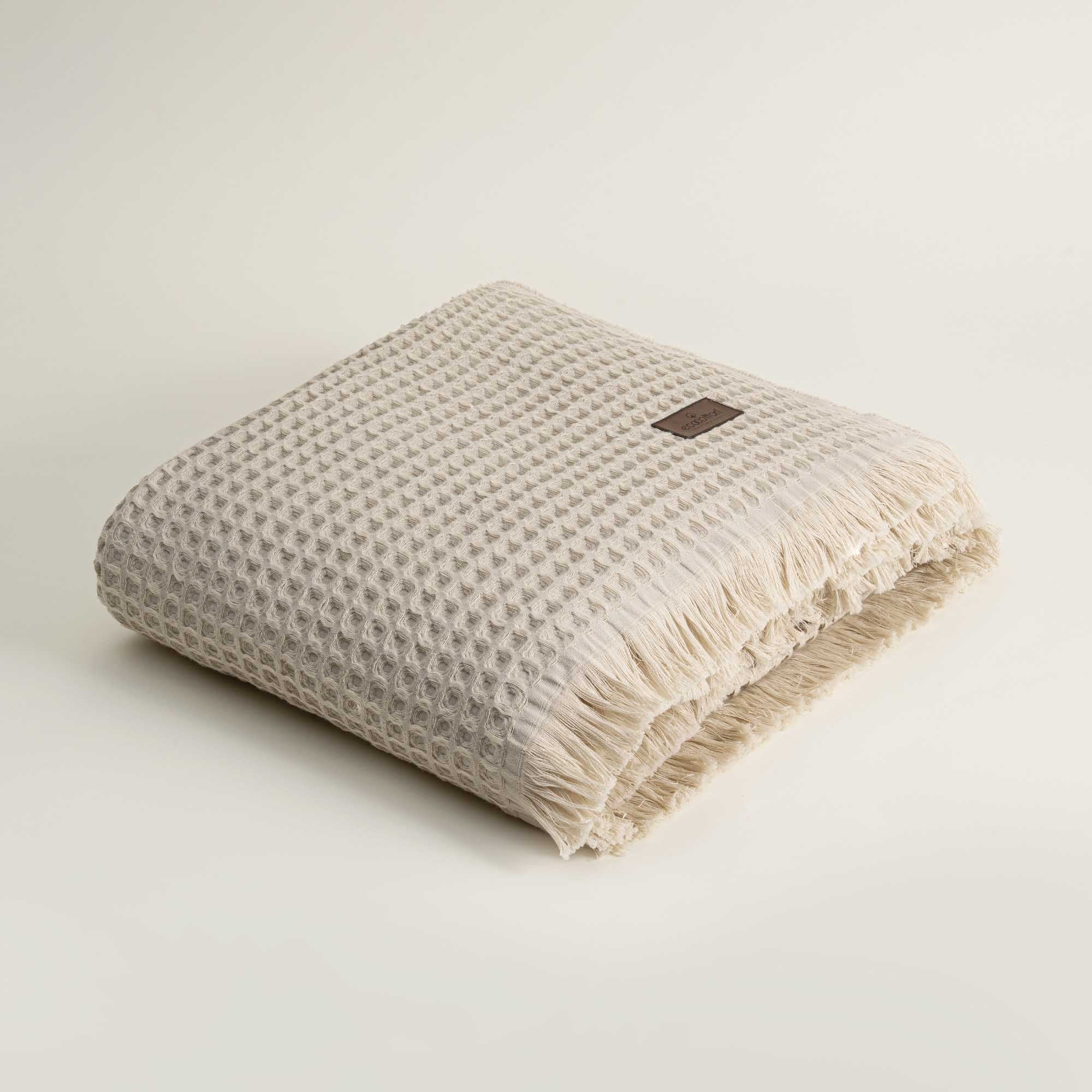 Beige textured towel with frayed edges on a light beige background