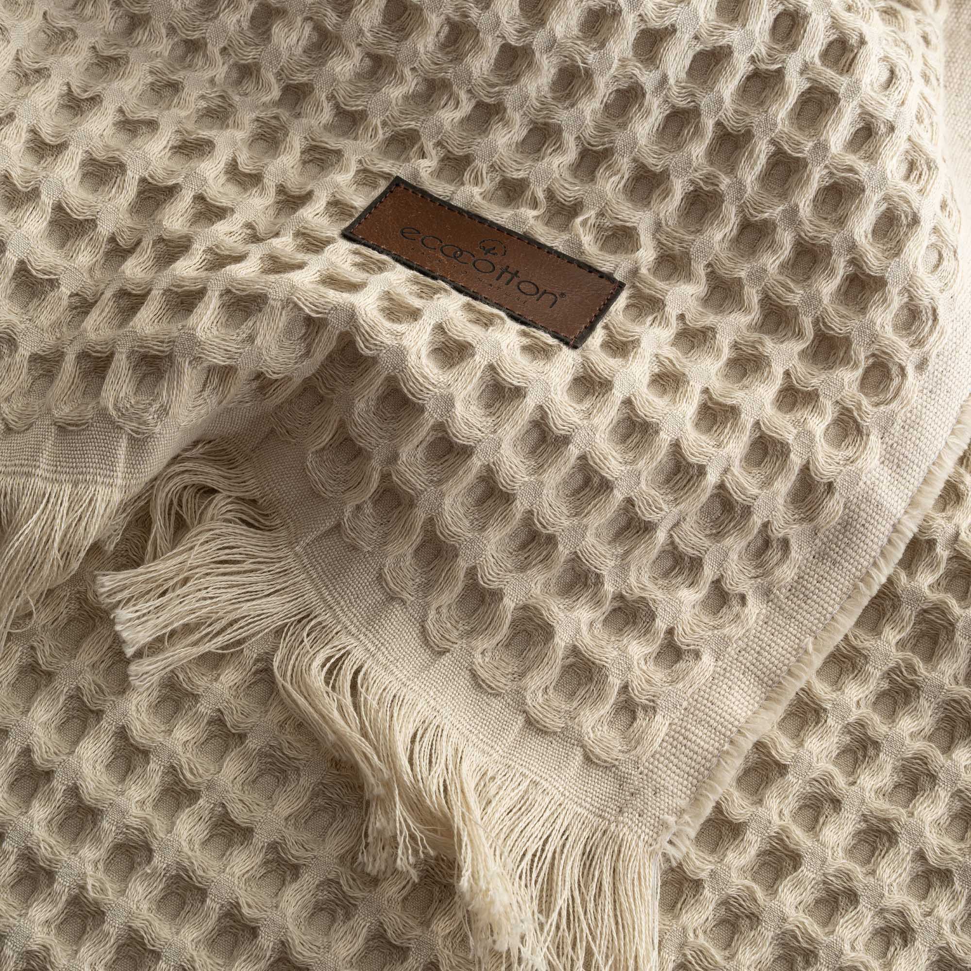 Close-up of Ecocotton tag on beige Organic Aegean Seren Waffle Large Throw/Bed Spread 400-gram, emphasizing its eco-friendly certification and premium organic cotton quality