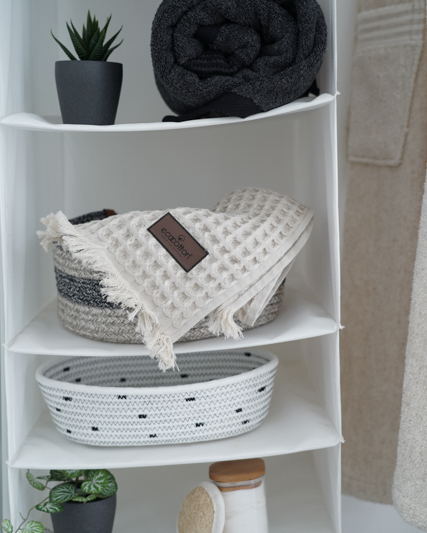 Minoa USA Canada Seren organic cotton waffle luxury bath towels stocked on a shelf with bath tools, highlighting their plush texture and sustainable luxury