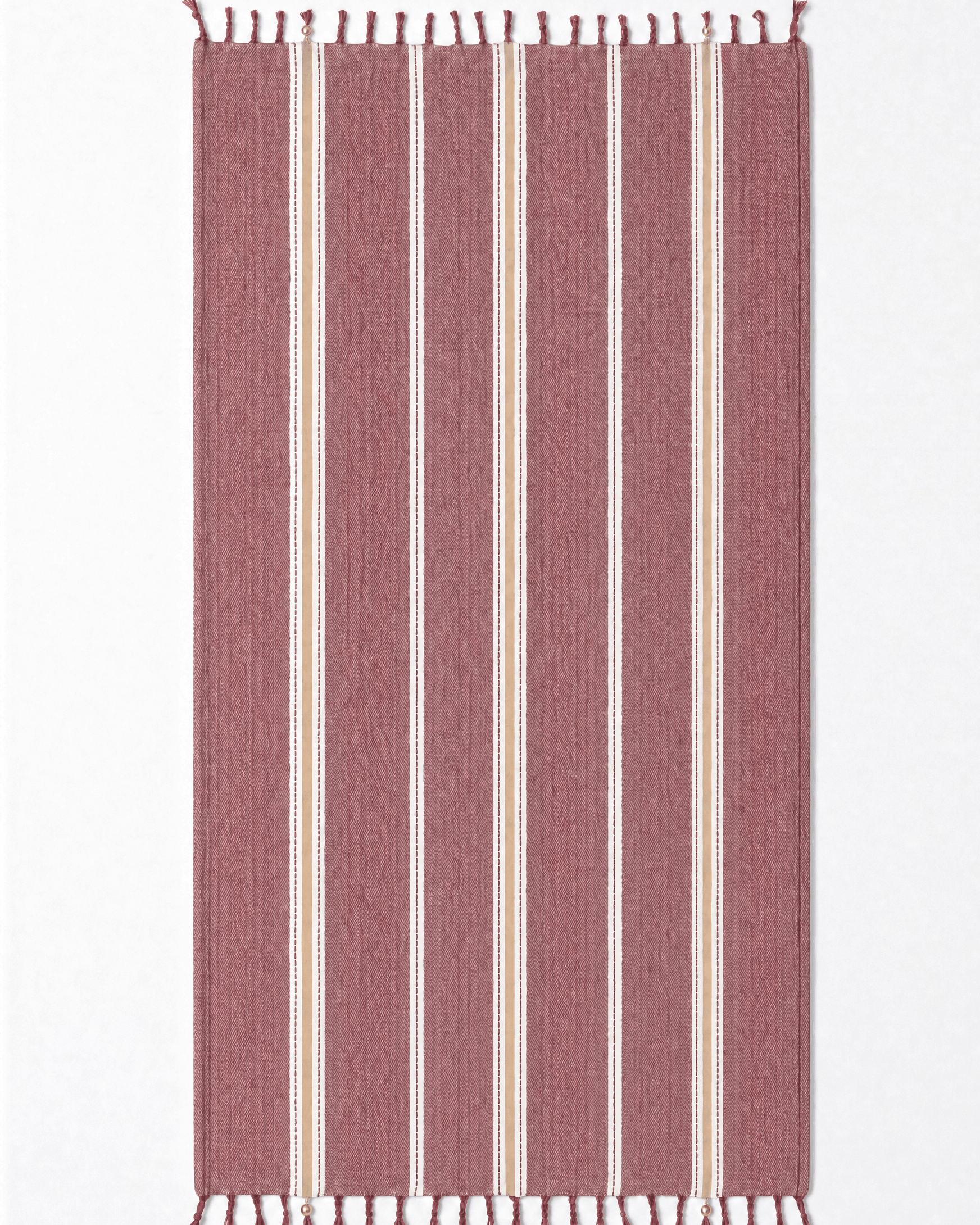 A rectangular woven towel with vertical stripes in dusty rose, cream, and white, finished with small fringe tassels at the top and bottom, shown flat against a plain white background.