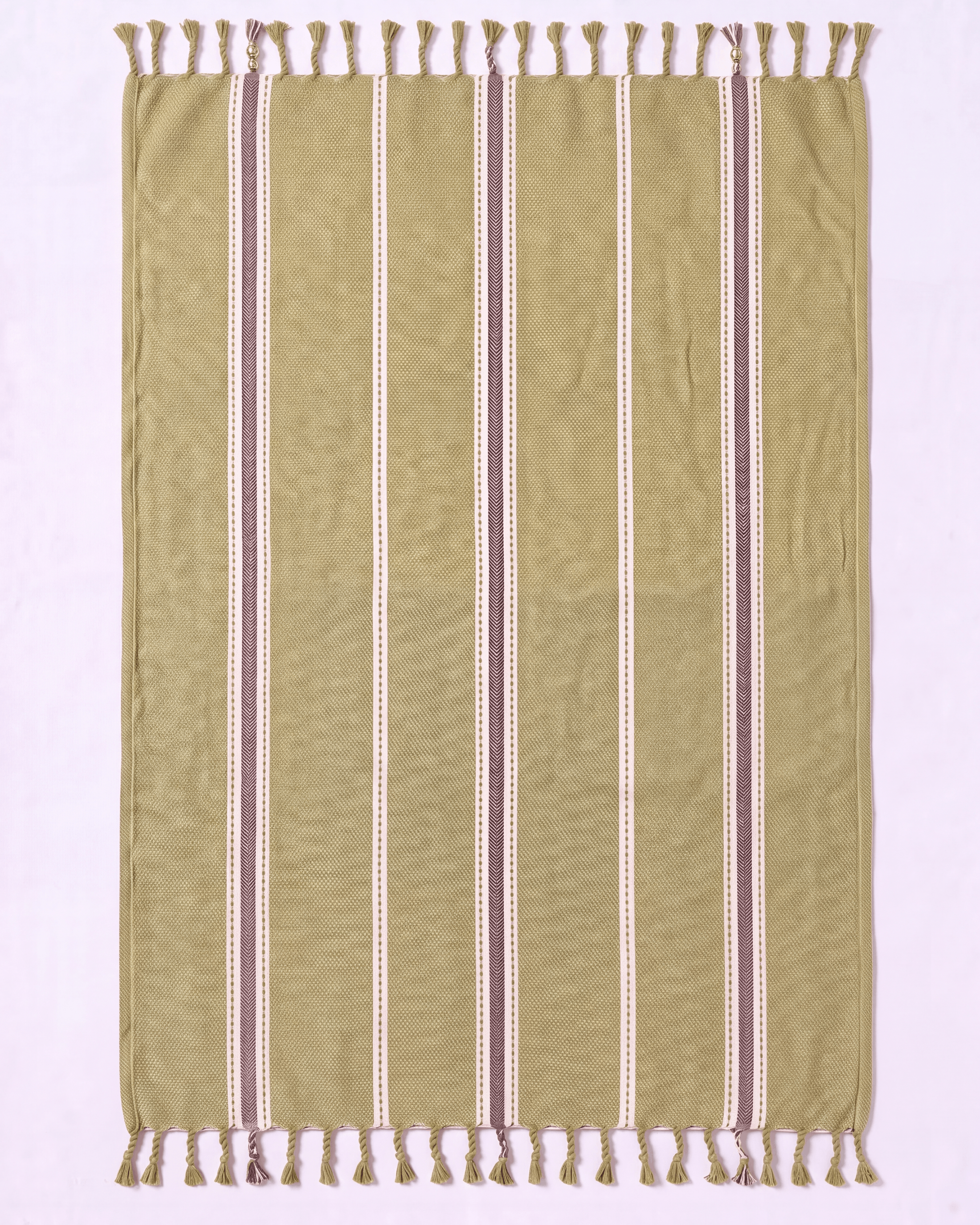 A rectangular woven towel with fringe on both short ends, shown flat against a pale pink background. The fabric is predominantly olive green with vertical stripes in cream, white, and muted mauve-brown.