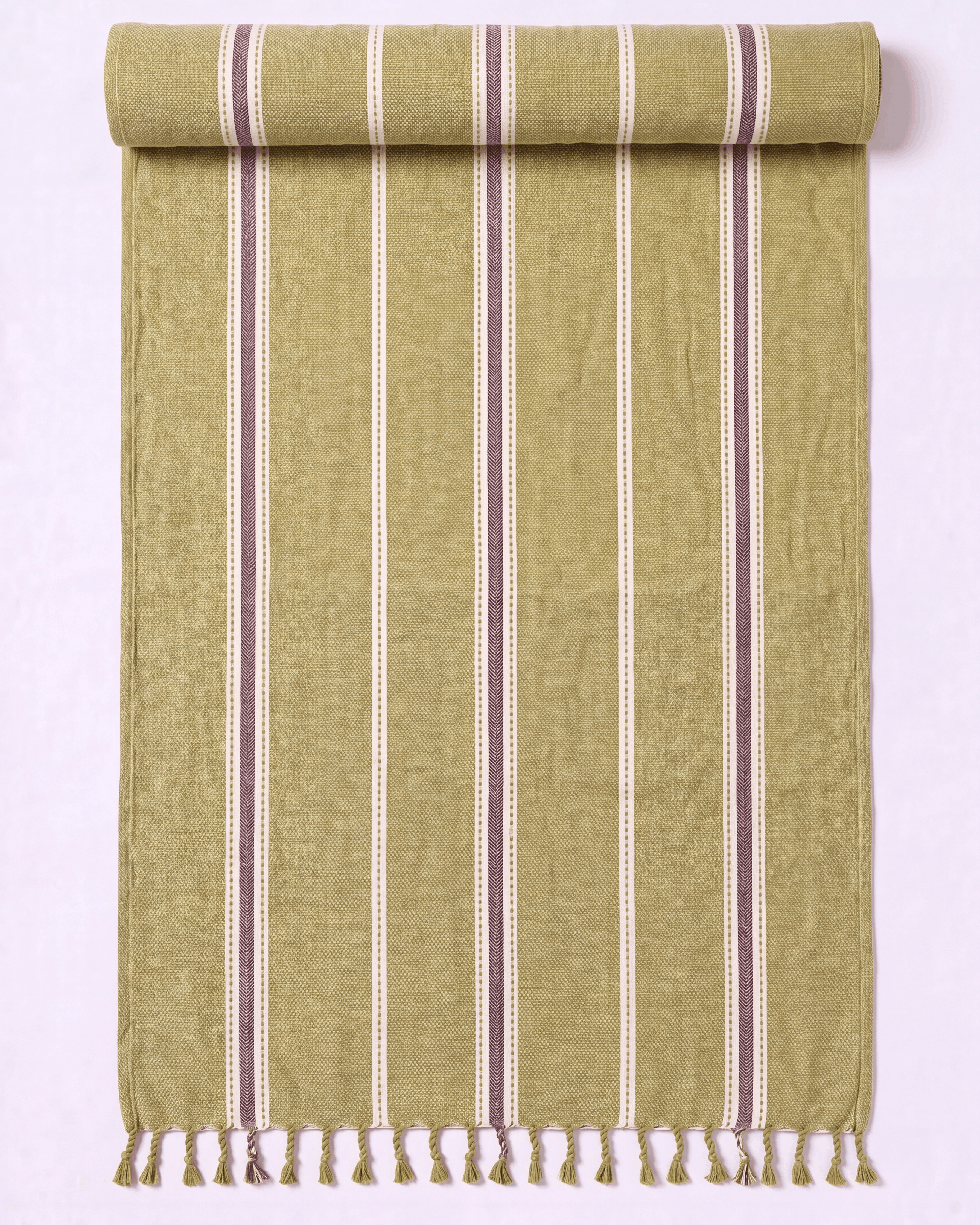 A rolled-out woven towel in a muted olive green color with vertical stripes in cream and dark brown, finished with a fringed tassel edge.