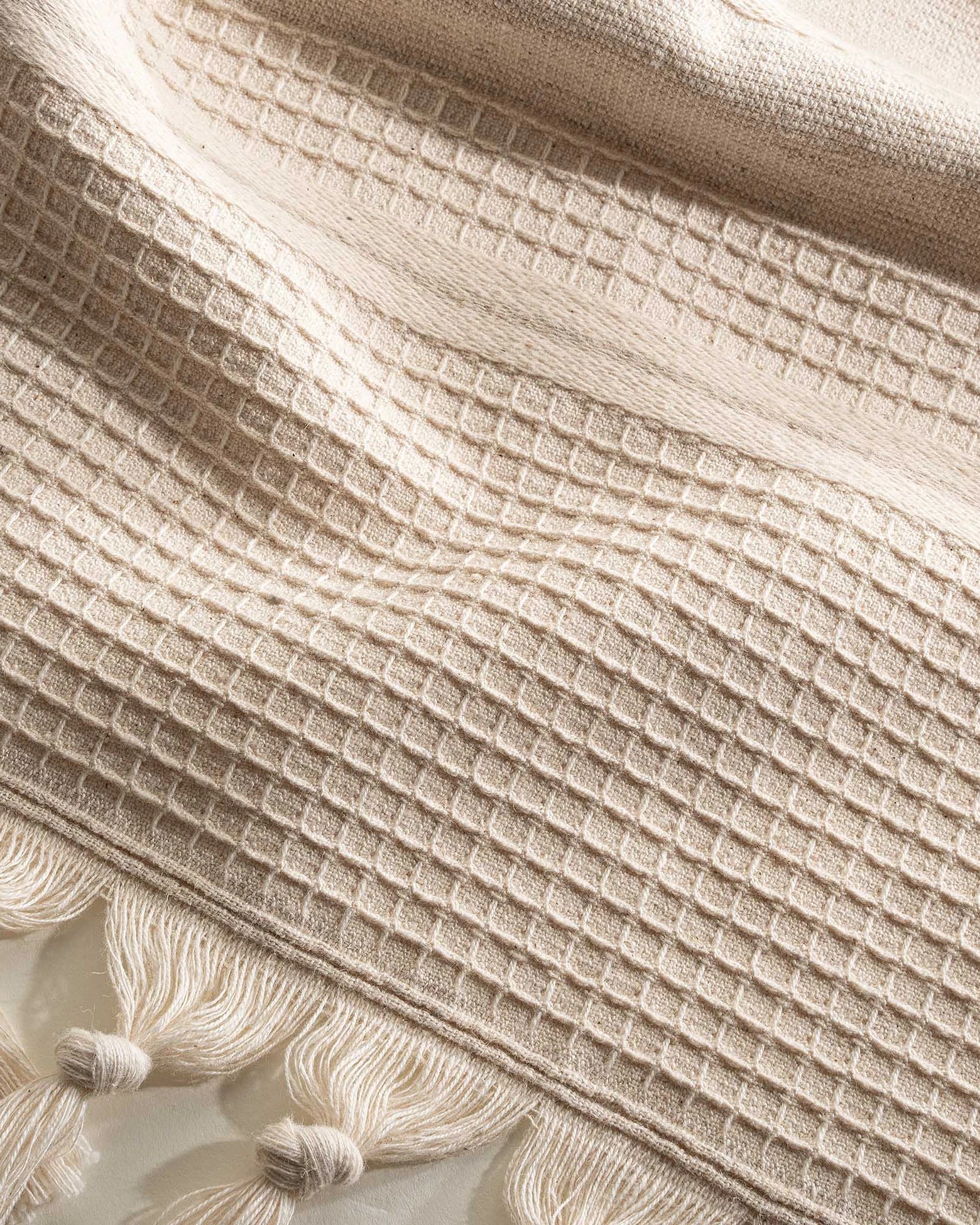 Close up of the Arden Hemp and Organic Cotton Bath Towel with tassels in sand and white showing the soft texture natural color and intricate tassel details of this luxury bath towel and organic bath towel