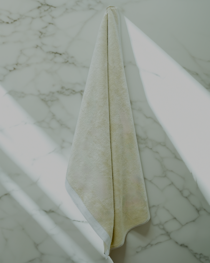 Monte Rosa 820-gram organic Aegean cotton luxury bath towel set with a single Raw Elegance towel elegantly hanging on the wall, showcasing soft plush texture and sustainable luxury