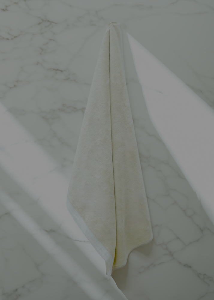 Monte Rosa 820-gram organic Aegean cotton luxury bath towel set with a single Raw Elegance towel elegantly hanging on the wall, showcasing soft plush texture and sustainable luxury