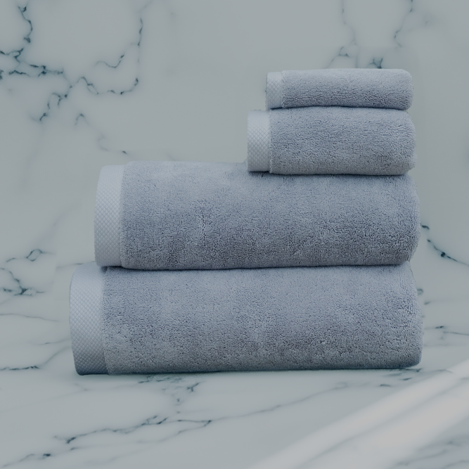 Stacked grey luxury bath towel set from Minoa Home on a marble surface, featuring hand, face, and bath towels for a complete bath collection.