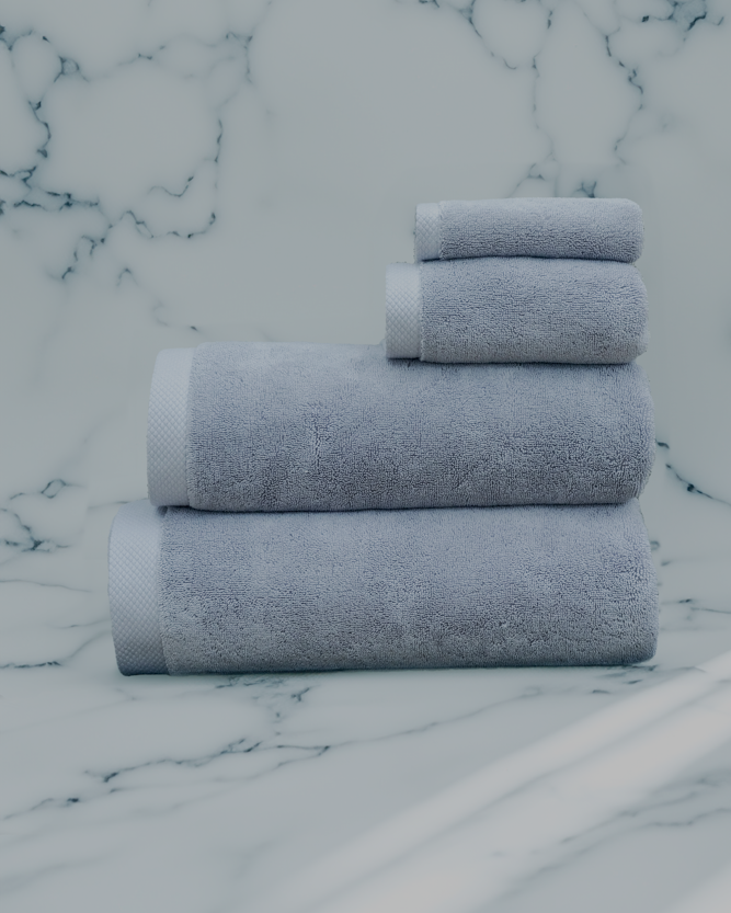 Stacked grey luxury bath towel set from Minoa Home on a marble surface, featuring hand, face, and bath towels for a complete bath collection.