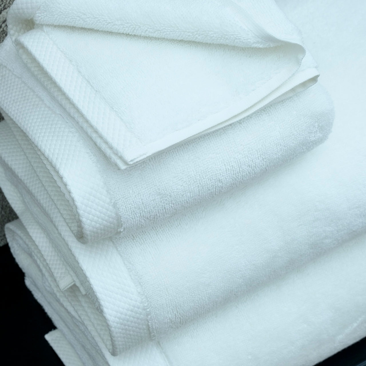 Stack of ultra soft luxury bath towels from Minoa Home made with premium organic cotton, showing the textured detail and Minoa branding tag