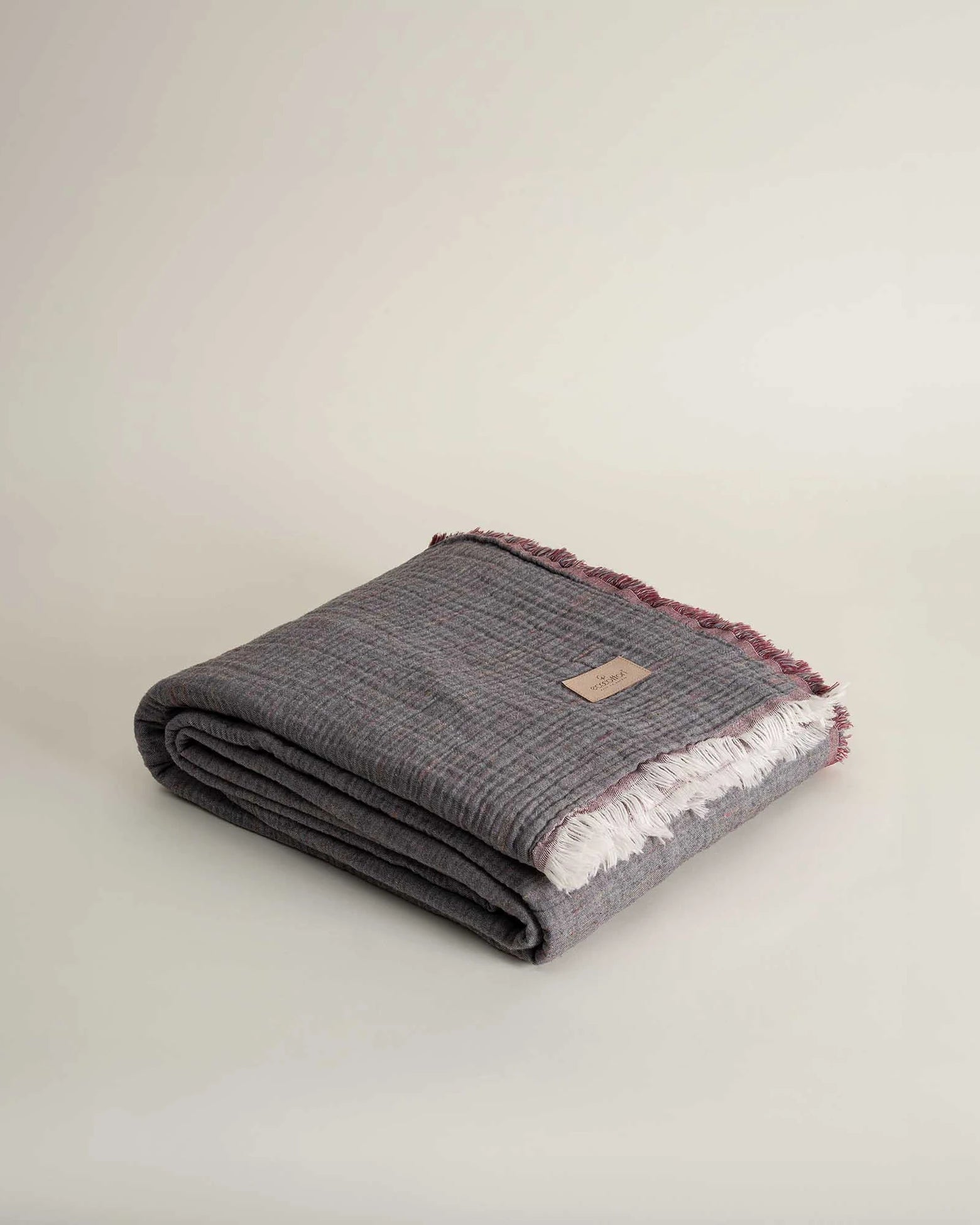 Folded reversible Muna organic gauze bed spread in Terra, neat folds, soft texture, earthy tone with organic cotton sheets.