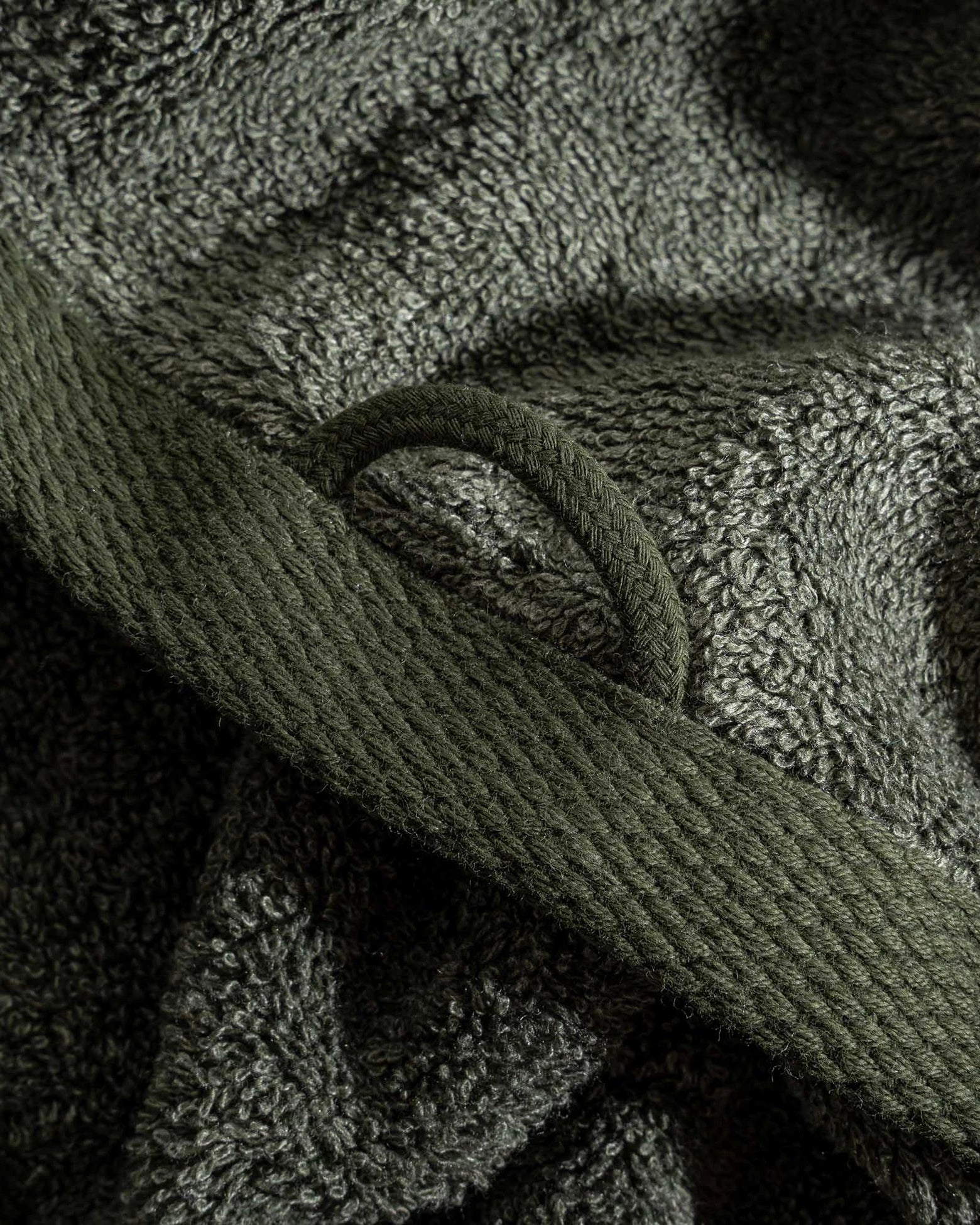 Two folded Minoa USA Canada luxury bath towels from the Naia and cotton collection in Mossy Muse, featuring a round loop for hanging and highlighting soft texture, natural color, and premium fabric