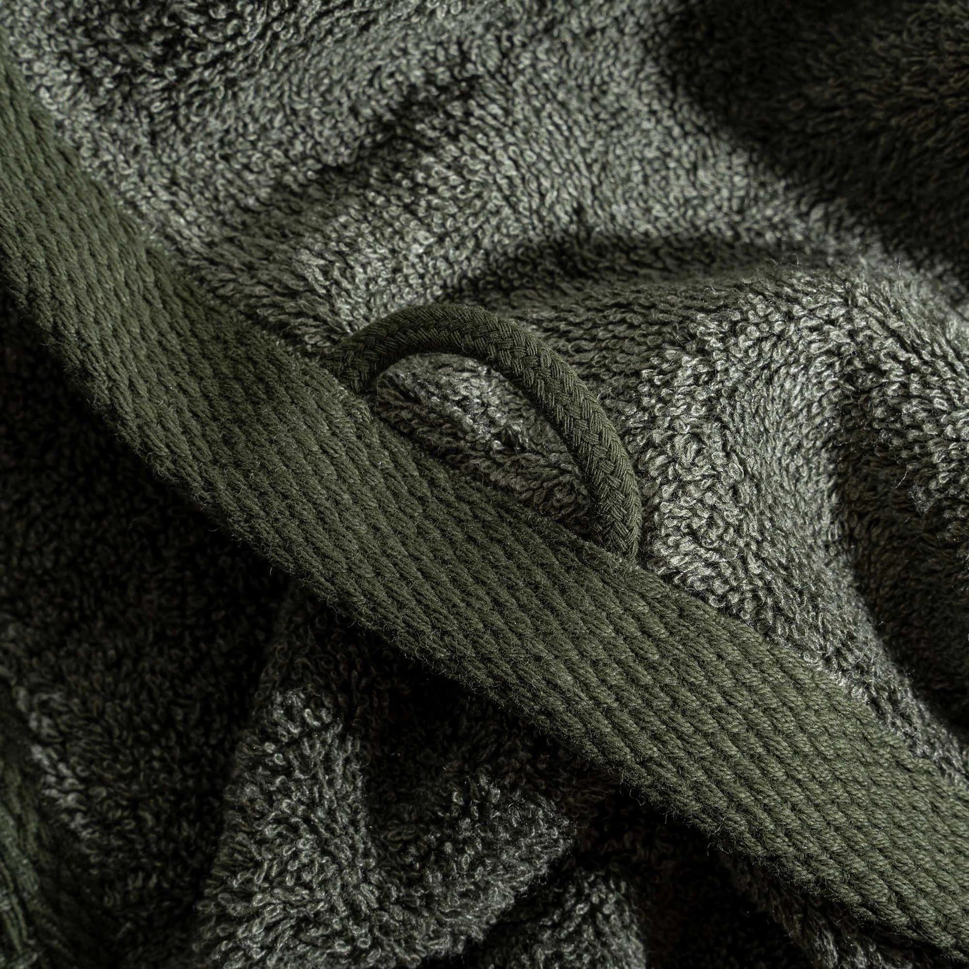 Two folded Minoa USA Canada luxury bath towels from the Naia and cotton collection in Mossy Muse, featuring a round loop for hanging and highlighting soft texture, natural color, and premium fabric