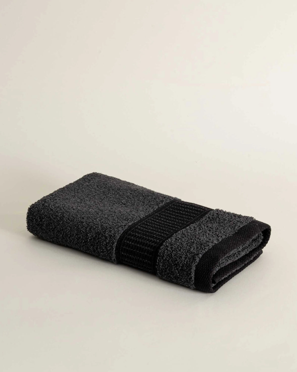 Folded dark gray towel on a beige background