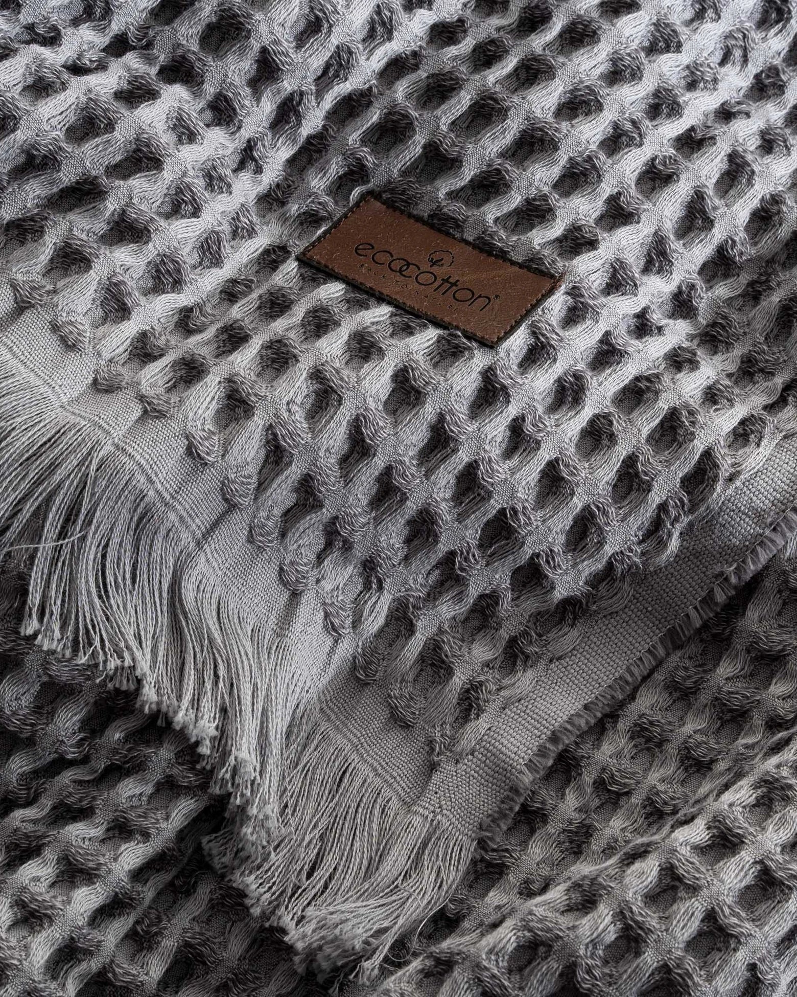 Close-up of Ecocotton tag on Organic Aegean Seren Waffle Large Throw 400g in Silver Suede, eco-friendly premium organic cotton sheets.