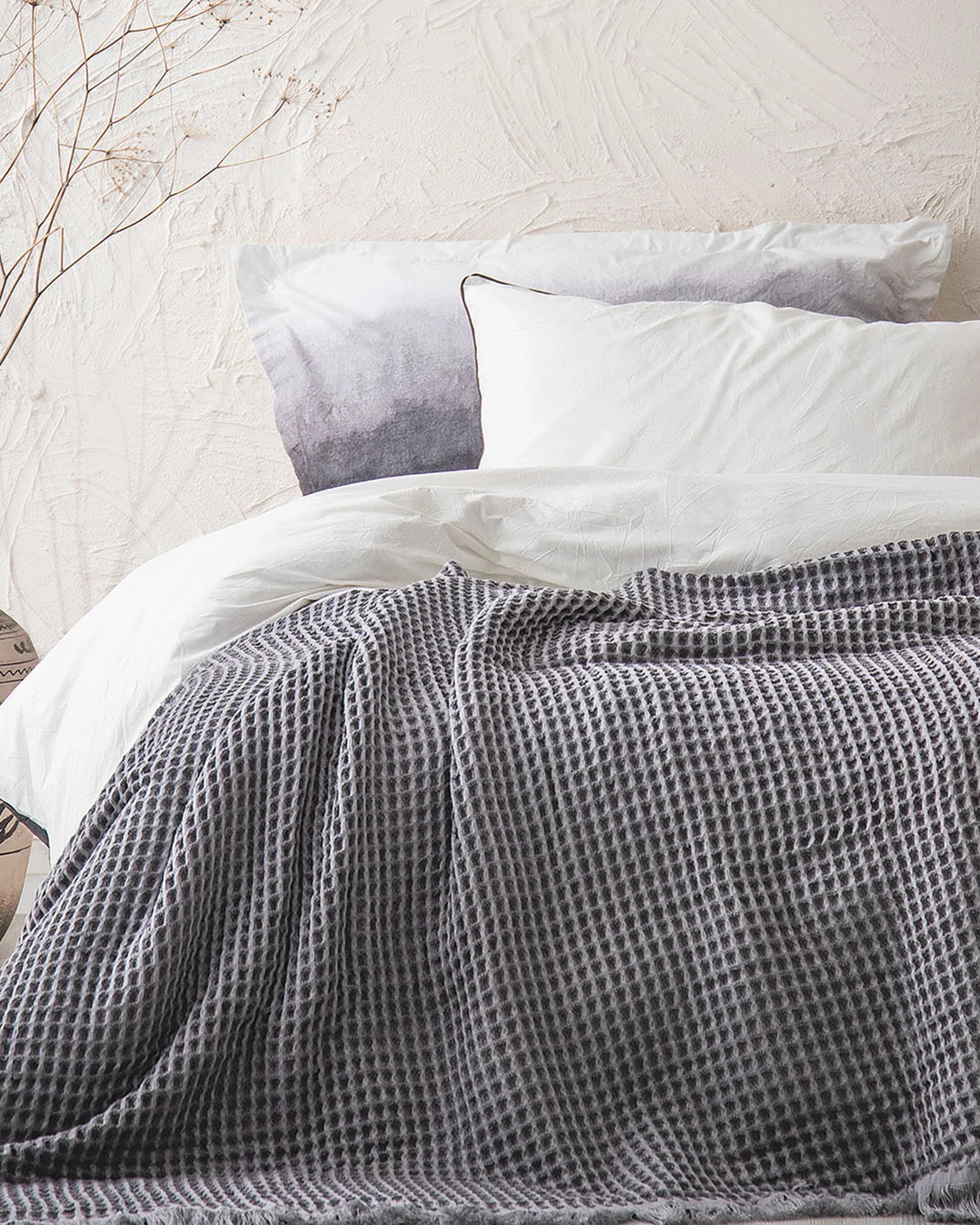 Organic Aegean Seren Waffle Large Throw 400g in Silver Suede on white bed, soft luxurious texture with organic cotton sheets.