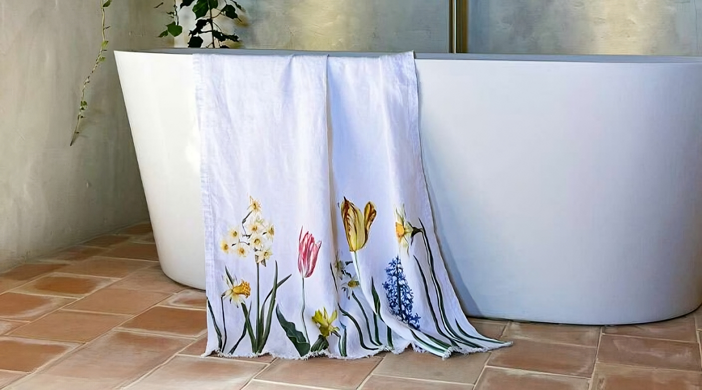Floral-patterned towel draped over a white bathtub in a bathroom setting.