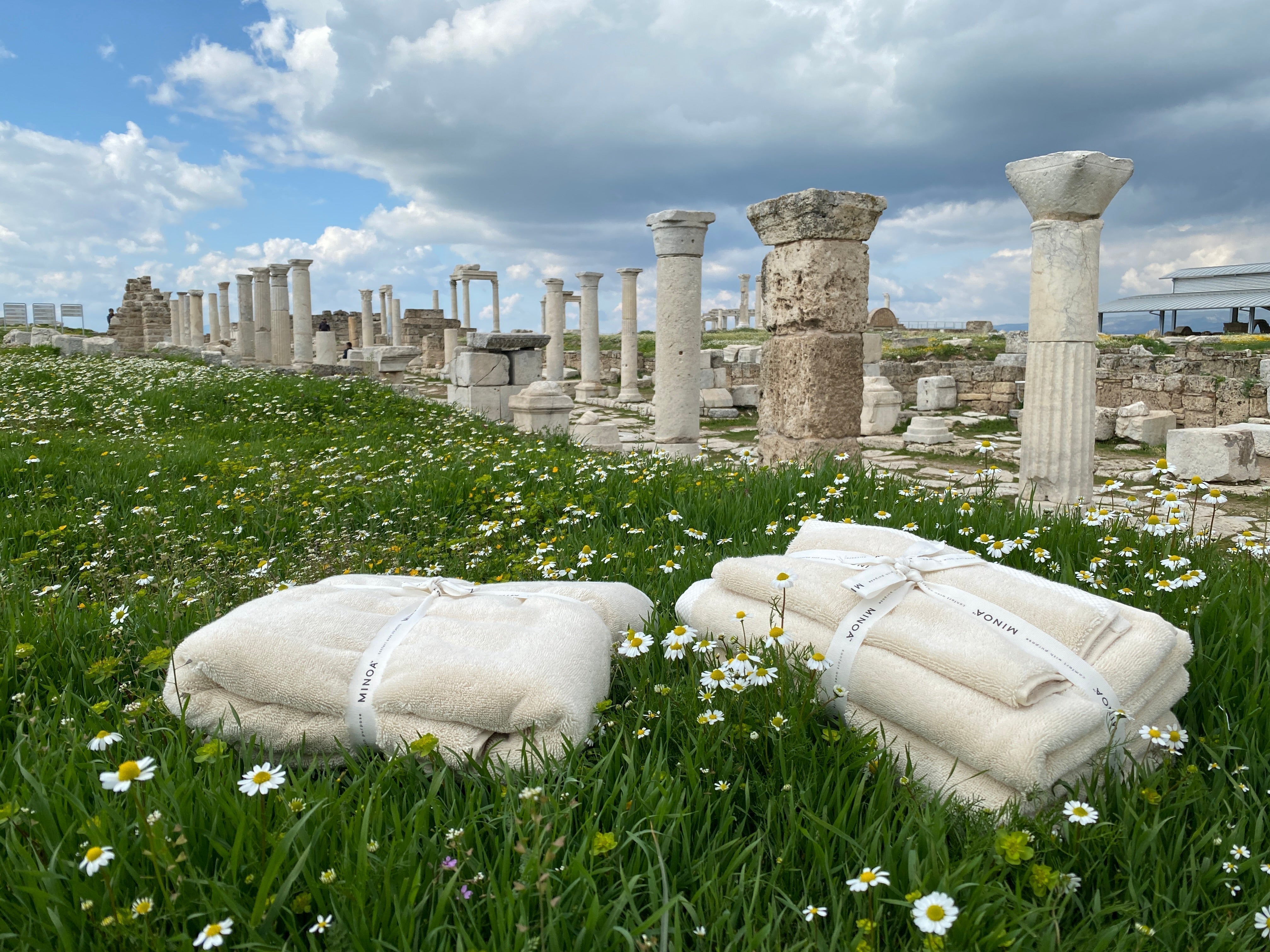 Two Minoa aegean cotton towels laying on the grass