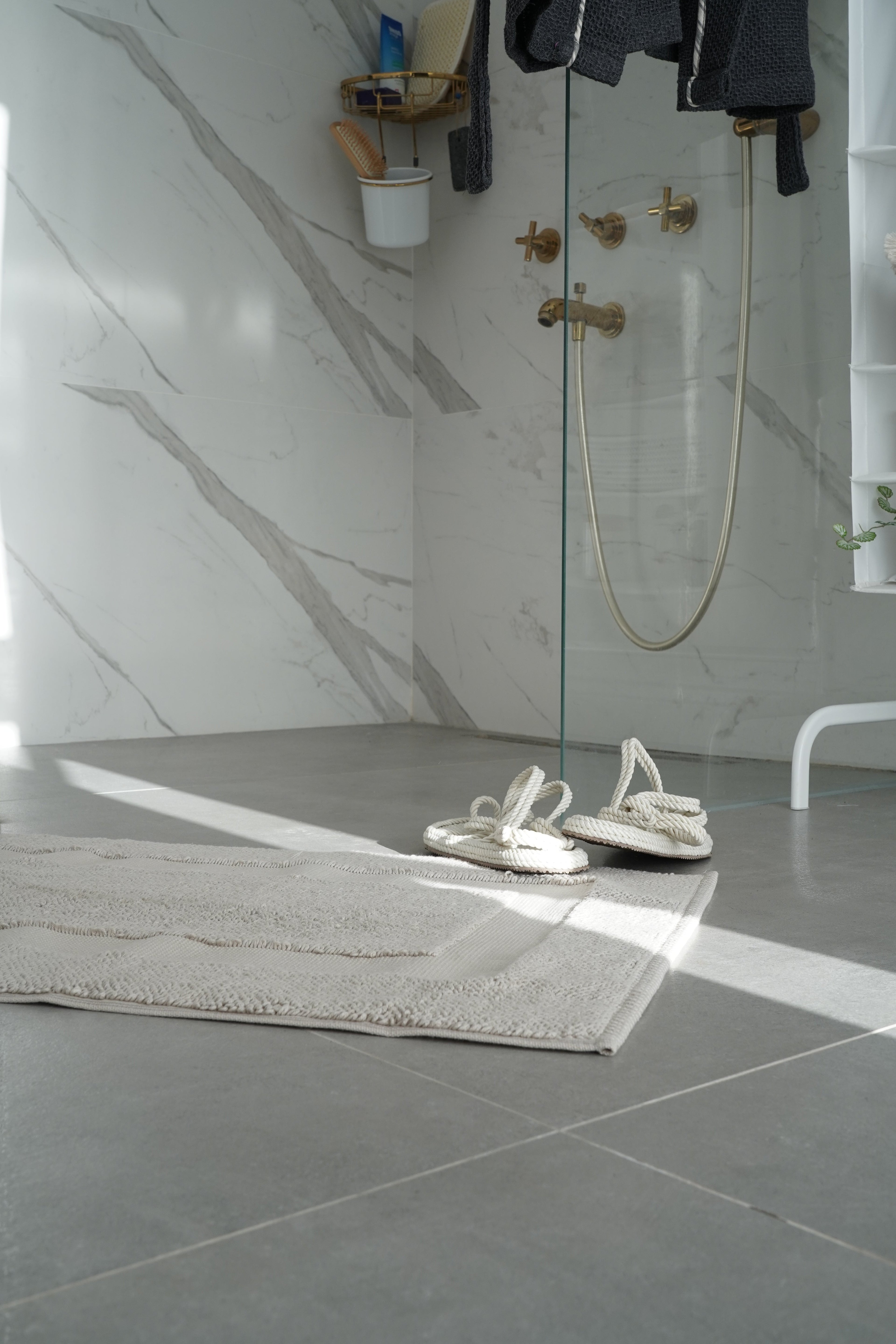 White bath matt with white slippers on the bathroom floor