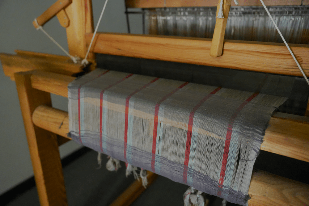 Woman sewing fabric with a sewing machine in a workshop setting.