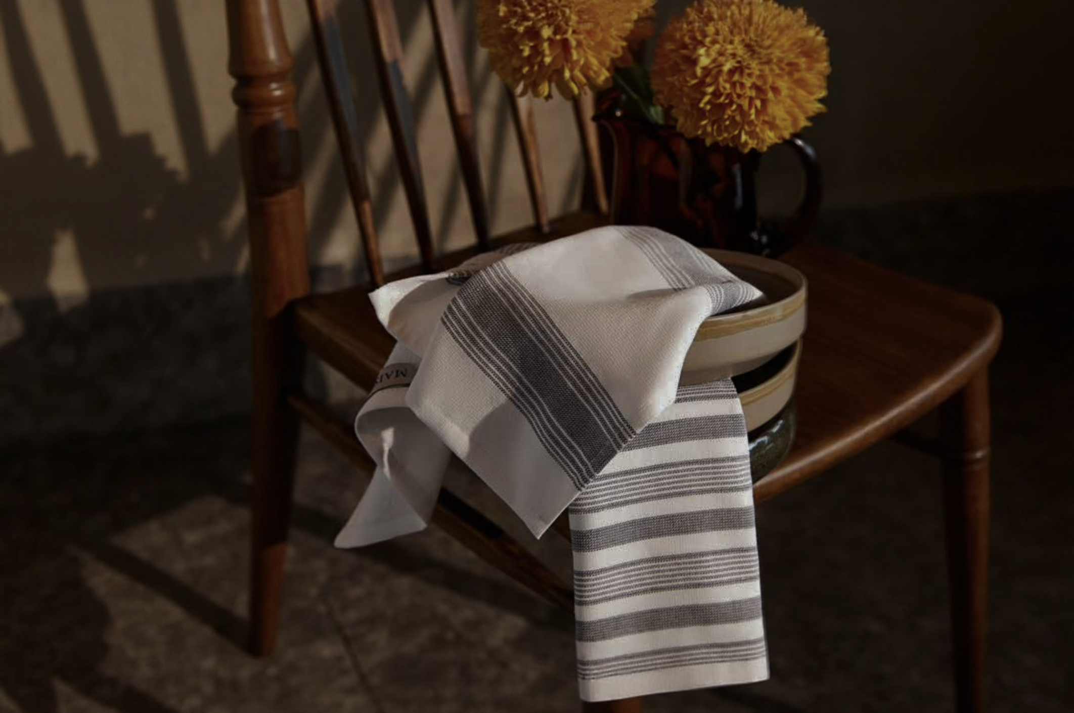 Striped beige kitchen towel made from sustainable cotton, elegantly draped over a modern drawer handle—Minoa Home’s eco-friendly kitchen linen for everyday use.