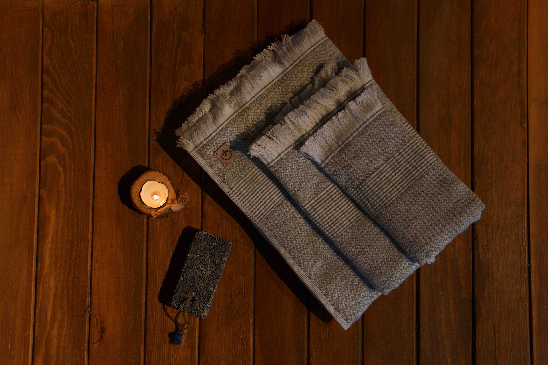 two pieces of Minoa's bath towels laying on a table with a light beside it